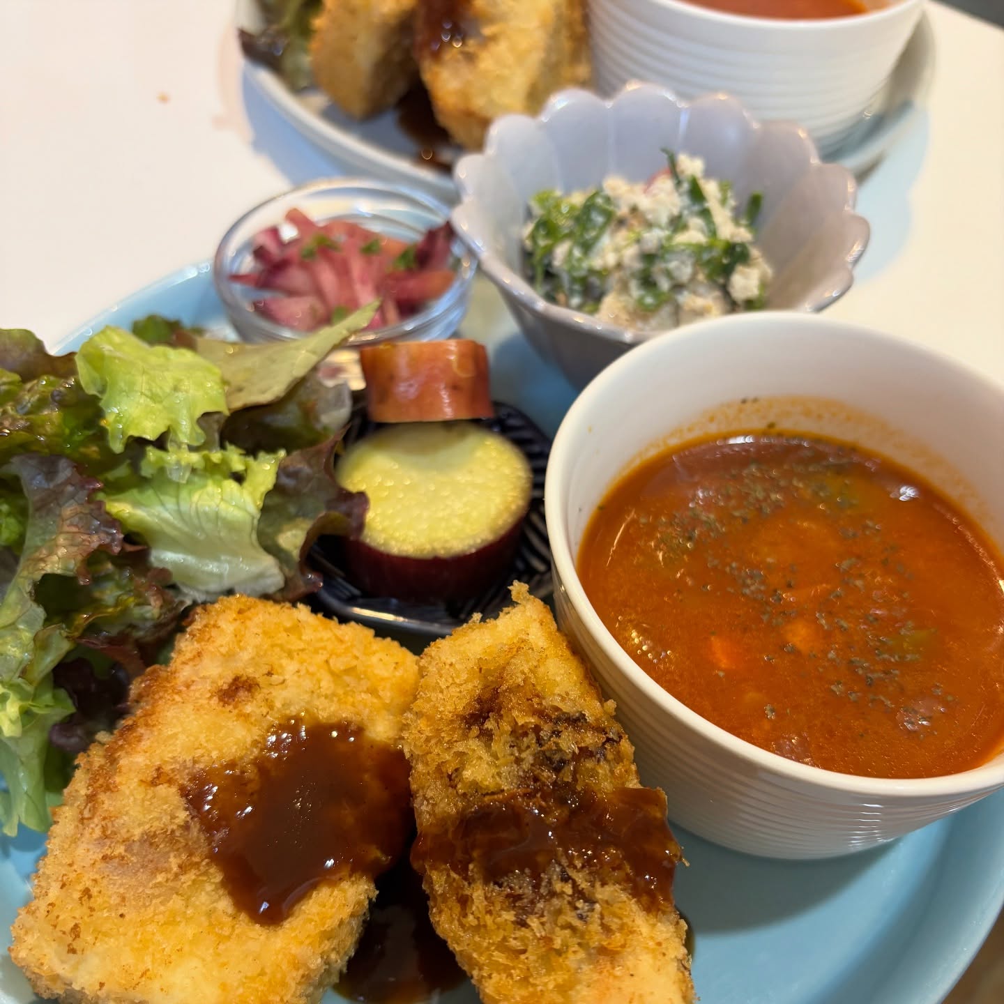 今週のプレート高野豆腐の挟み揚げ大豆ミートとヴィーガンチーズを間に挟んでパン粉で揚げました。ボリュームある一品です。セリとりんごの白和え藤くるり大根のナムルサツマイモのレモン煮トマト豆スープ雑穀ご飯明日のスイーツはシナモンりんごのクランブルタルトオレンジパイナップルのクッキーサンド豆腐のチョコレートスパイスキャロットケーキヴィーガンスコーンプレーンその他クッキーテイクアウトございますよろしくお願いいたします